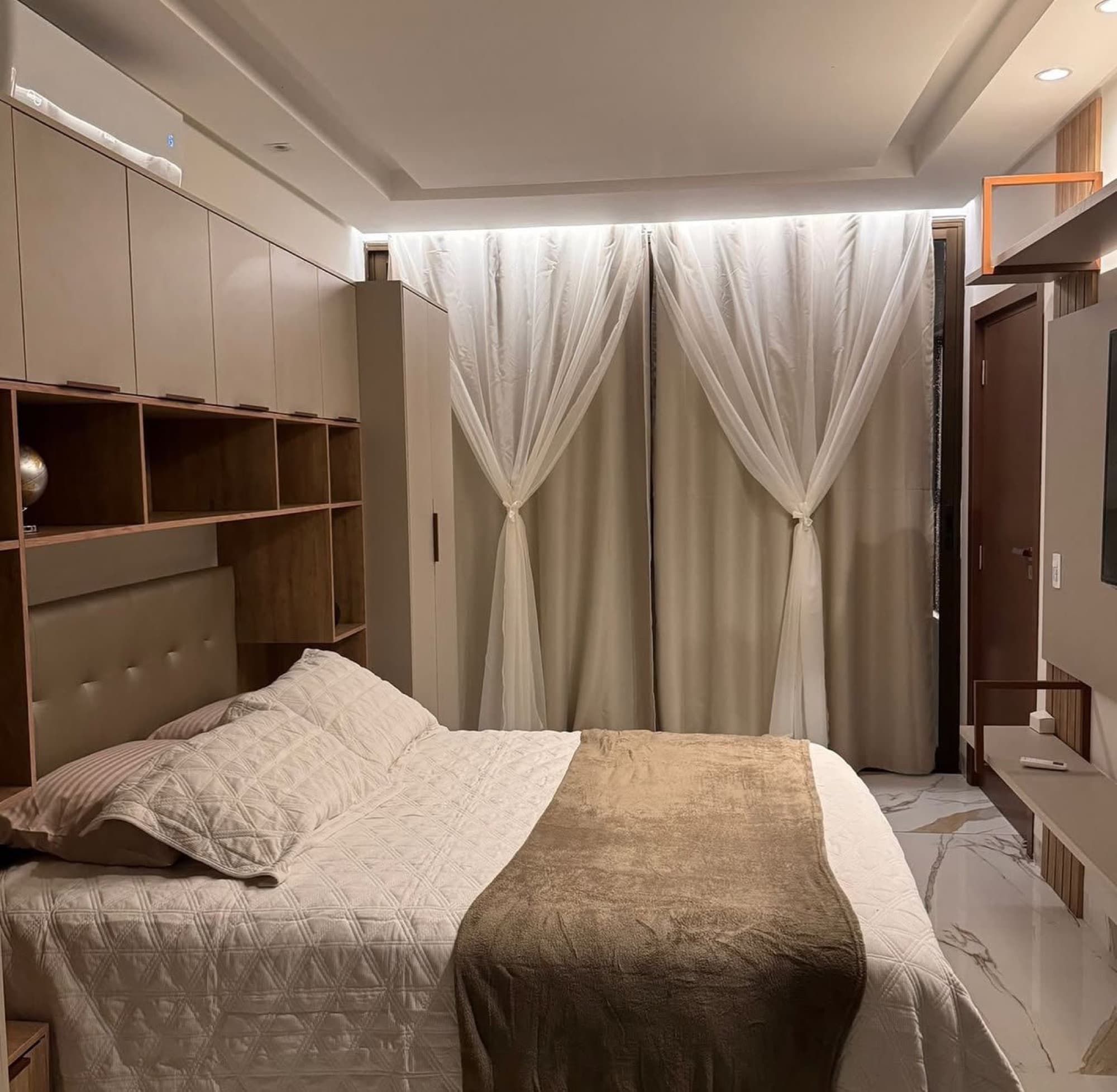 Suíte com cortinas de véu e iluminação aconchegante